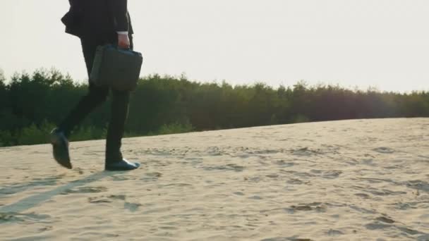 ケースを持ったビジネスマンが消える、フレームは、足だけを見て。砂の上を行く — ストック動画