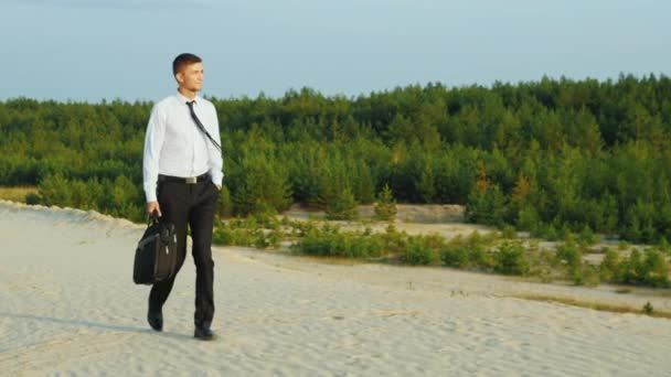 Zorgeloos gelukkig zakenman praten op het zand tegen de achtergrond van een prachtig bos. Het concept - get away from werk en problemen, uitstappen in de natuur — Stockvideo