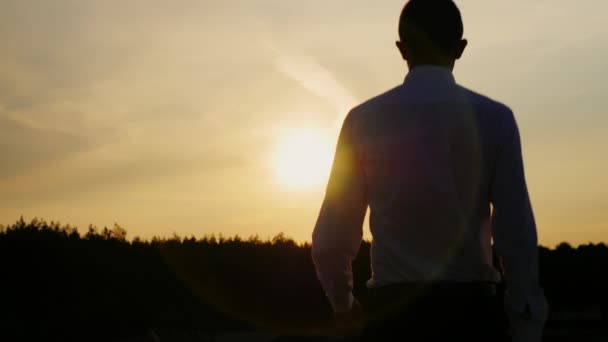Nuevos horizontes de negocio. Un joven hombre de negocios con un traje mirando al amanecer. Concepto: esperanza, confianza, sueño — Vídeos de Stock