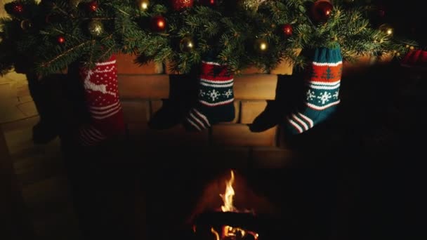 Estamos esperando a Santa Claus. Calcetines para regalos colgando sobre la chimenea en llamas — Vídeo de stock