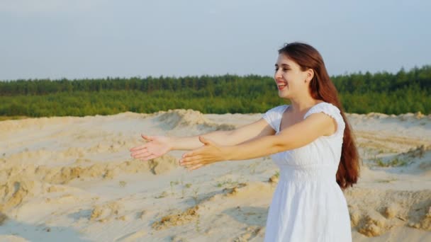 Attraktive junge Mutter spielt mit ihrer Tochter und umarmt sie. sitzen im Sand gegen den blauen Himmel — Stockvideo