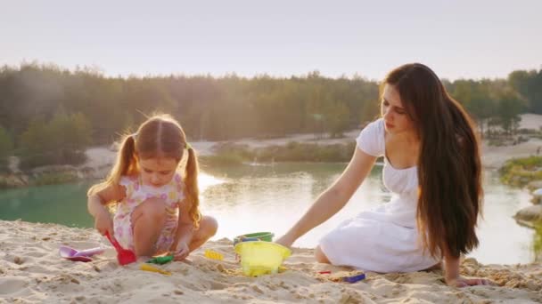 Moeder en dochter spelen in het zand, gegoten beeldjes uit zand. Gelukkige jeugd — Stockvideo