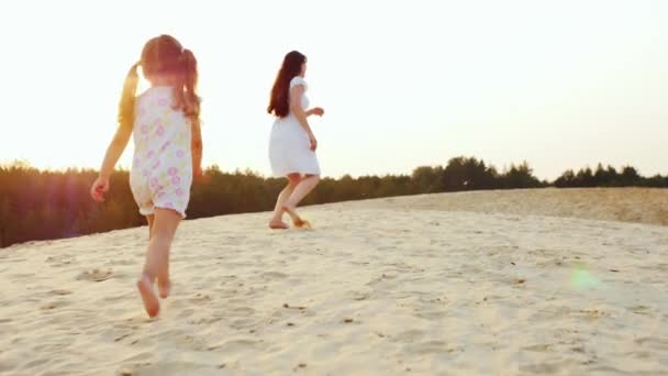 Мама играет с девушкой три года. Девушка бежит за своей матерью по песку. Счастливого детства — стоковое видео