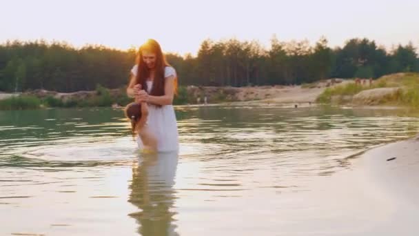 Juegos con niños. Madre e hija juegan en el agua en el río — Vídeo de stock