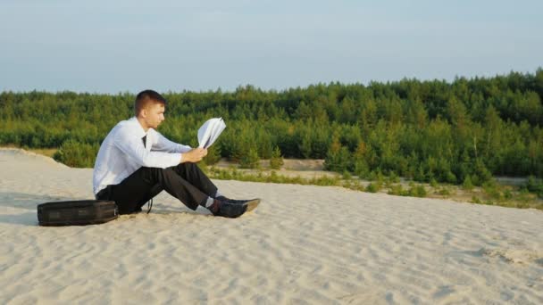 Het slechte financiële nieuws. Jonge zakenman lezen van documenten, dan werpt de vellen papier aan de wind — Stockvideo