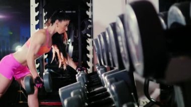 Kadın atlet spor salonunda bir dumbbell ile egzersiz yaparak. Sahne ışıkları altında