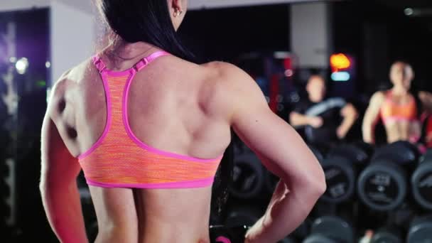 La motivación en el deporte. Mujer atlética mostrando sus músculos frente a un espejo. Ella mira a su entrenador: su cara está borrosa. Culturismo femenino — Vídeos de Stock