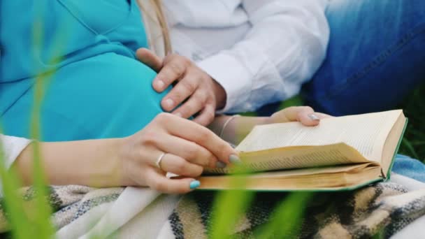 Mulher grávida e seu marido lendo um livro em uma cena não vista pessoas — Vídeo de Stock