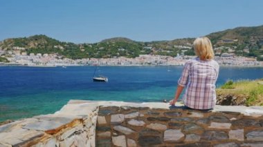 Atış Steadicam: güneş gözlüklü kadın turist deniz manzarasına hayran. Cadaques Akdeniz şehir İspanya fonunda