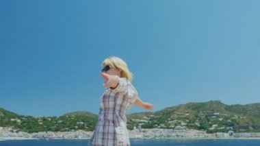 Atış Steadicam: genç kadın sahiptir Akdeniz beldesinde rahatlatıcı. Ellerini sallayarak, kaplıca kenti ve deniz arka planda duruyor