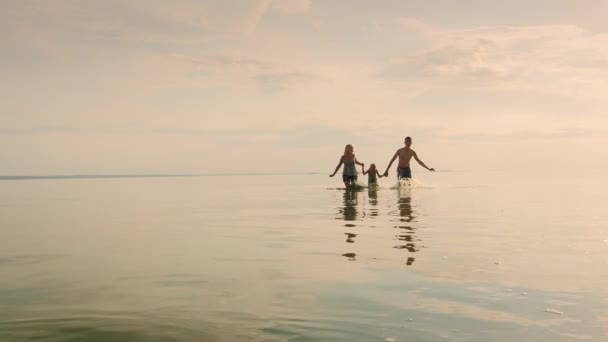 Diversión familiar en vacaciones. Salió corriendo del agua al atardecer levante spray — Vídeo de stock