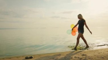 Kaygısız genç kadın kesiminden plajda güzel gökyüzünde balonlar holding