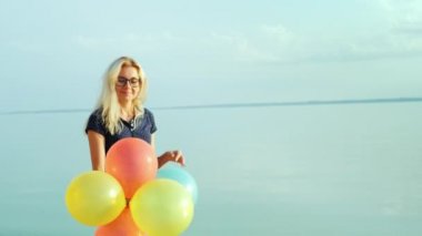 Denizde Balonlu mavi gökyüzü bir arka plan üzerinde yürüyen genç bir kaygısız kadın portresi