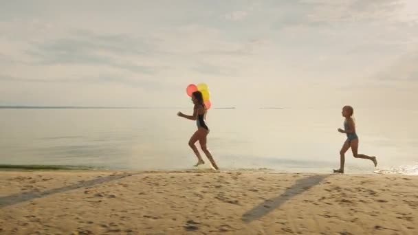 Boldog gyermekkor - két lánytestvére fut egymás körül a strandon. jó szórakozást — Stock videók