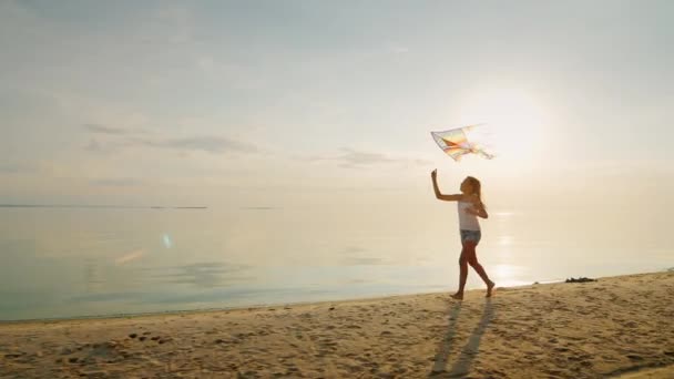 Ragazza spensierata corre lungo la spiaggia, giocando con un aquilone. Il concetto - un'infanzia spensierata e felice — Video Stock