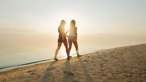 Mãe e filha são adolescentes na praia ao pôr-do-sol. Visão traseira — Vídeo de Stock