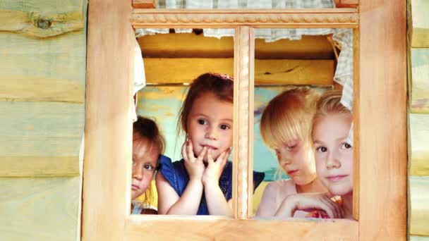 Cuatro chicas miran por la ventana a la casa de los niños — Vídeo de stock