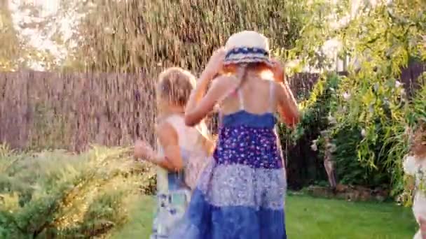 Zorgeloos plezier kinderen in de tuin spelen. Lachen, uitgevoerd onder de jets van het water of regen — Stockvideo