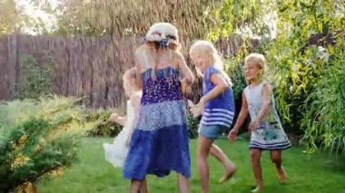 Çocuklar yaz bahçede oynarken. Su jetleri veya yağmur altında grupa çocuk iyi eğlenceler