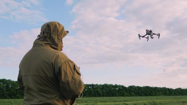 De man regelt de drone, de drone vliegt hoog aan de hemel: de camera volgt de drone — Stockvideo