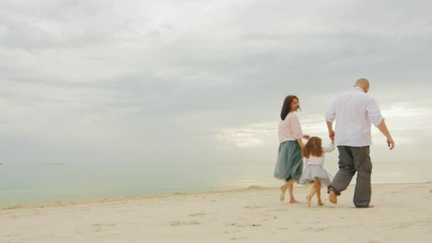 Família feliz juntos caminhando ao longo da costa de um mar calmo. Mãe pai e filha três anos — Vídeo de Stock