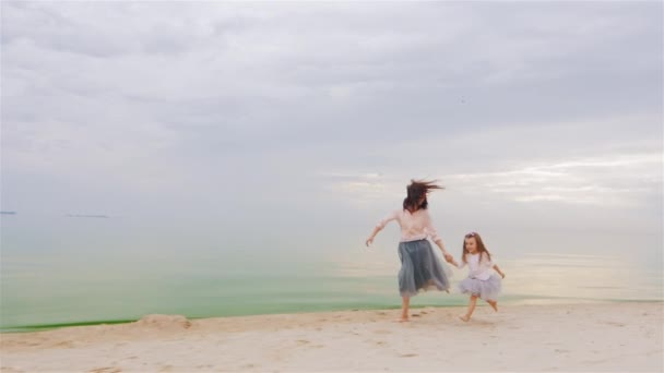 Ξέγνοιαστες νεαρή μητέρα που τρέχει με την κόρη της τρία χρόνια στην παραλία. Με φόντο ένα όμορφο ηλιοβασίλεμα ουρανό — Αρχείο Βίντεο