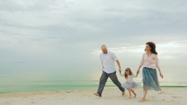 Gelukkige familie van drie mensen lopen op het strand. Leuke spelletjes met kinderen — Stockvideo