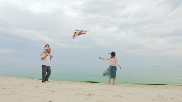 Genitori spensierati e felici che giocano con figlia e aquilone. Sulla spiaggia — Video Stock