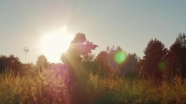 Steadicam yavaş çekim atış: Saldırıda silahlı erkeklerin silueti. Güneşte kollarıyla koşar