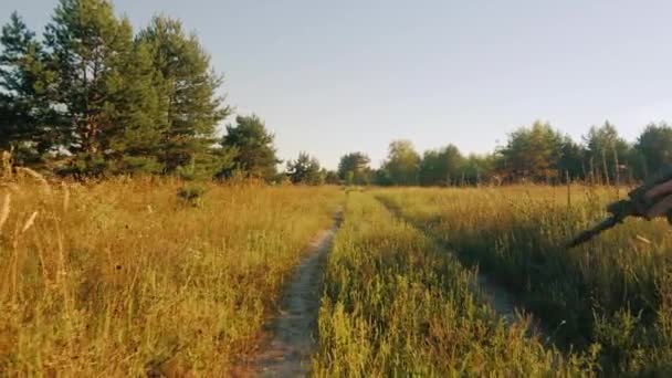 Steadicam geschoten: gewapende mannen in camouflage wandelen langs een landweg. Achteraanzicht — Stockvideo