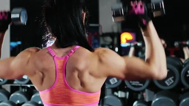 Zelfbewuste atletische vrouw is betrokken in een sporthal. Treinen met een halter — Stockvideo