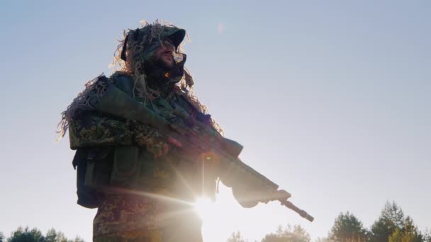 Ozbrojený muž v vojenské uniformě. Mělo by to být proti obloze, slunce září zpoza brnění — Stock video