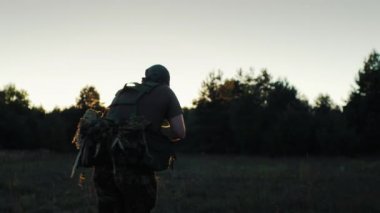 Askeri üniformalı bir adam gün batımında silahla koşarak saldırdı. Geri görünüm