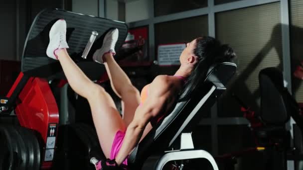Atletische vrouw traint spieren van de benen in de sportschool — Stockvideo