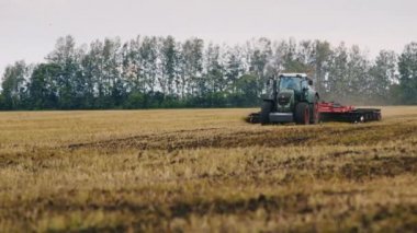 Traktör tarlaya doğru araziye doğru sürüyor. Uçup uçan bir kuş sürüsü