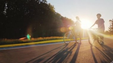 Steadicam çekim: Bir kadın oğlu genç ile yürür. Gün batımında kurşun bisiklet