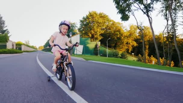 Funny blonde girl riding a bicycle in the park — Stock Video