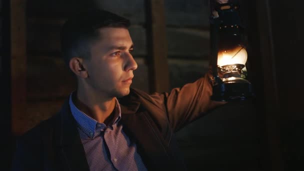 The tired young man in suit lights a path kerosene lamp — Stock Video