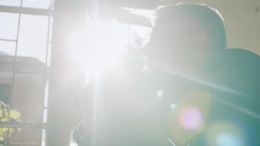 Pencere nin üzerinde oturan genç bir adam, maksatlı ya da dua ediyor. Parmaklarının arasından güneşin parlayan ışınları. Kavram: umut, inanç, din