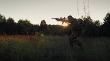 Steadicam yavaş çekim çekim: bir çalışan adamın silueti. Saldırıda silah tutan asker nişan aldı.