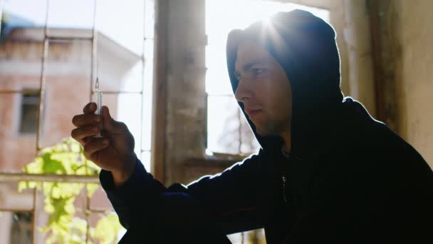 Ein junger Mann mit Kapuze wirft die Spritze mit der Droge. das Konzept - die Abhängigkeit zu überwinden: der Beginn des neuen Lebens, die Wiederbelebung — Stockvideo