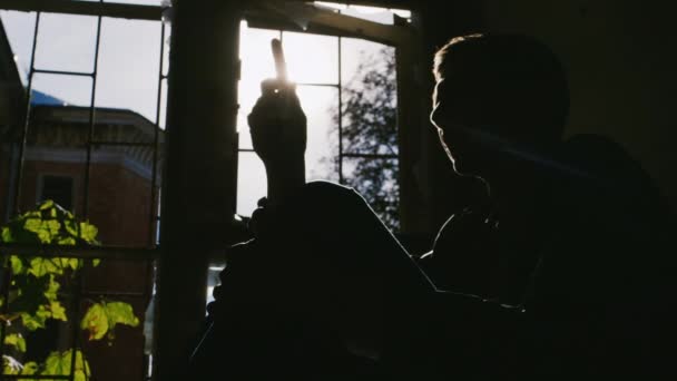 Nebezpečí drog. Mladý muž s injekční stříkačkou v ruce, sedící na slunci — Stock video