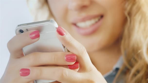 Mani di una giovane donna con un telefono cellulare, labbra sorridenti leggermente sfocate — Video Stock