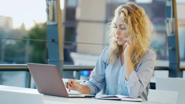 Attractive young woman working on site in summer cafe. It uses laptop — Stock Video