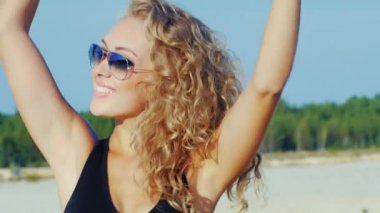 Plajda kameraya poz güneş gözlüğü ile çekici bir genç kadın. Gülümse -yen