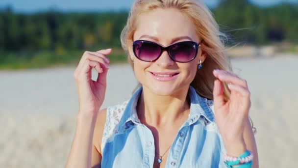 Piękna Blondynka kobieta uśmiechając się do aparatu, stwarzając. Summertime na plaży — Wideo stockowe