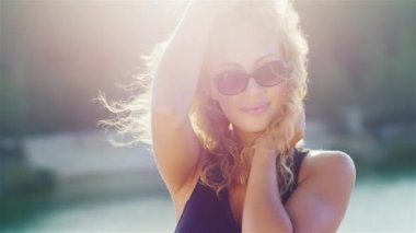 Seksi romantik bir kadının portresi. Batan güneşin ışınlarında, rüzgar saçında esiyor, gülümsüyor ve flört ediyor.