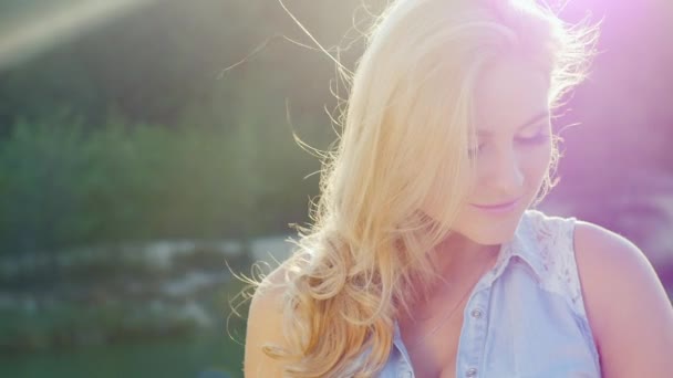 Blonde sexy posant pour la caméra, souriant, jouant avec les cheveux. Journée ensoleillée à la plage près de la mer — Video