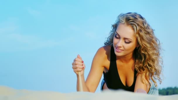 Aantrekkelijke jonge vrouw rustend op het strand. Spelen ligt tegen de hemel — Stockvideo