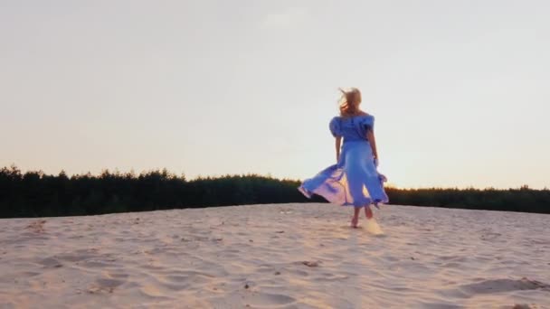 Steadicam slow motion shot: Uma jovem mulher em um vestido-ar leve corre ao pôr do sol na praia. Visão traseira — Vídeo de Stock